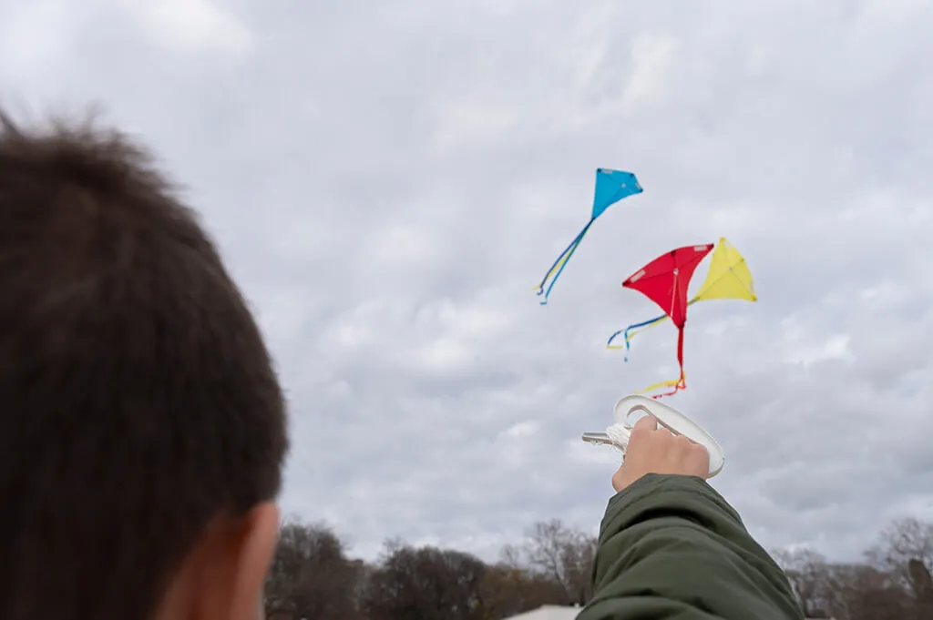 Young boy flying a bright kite in a scenic mountain town