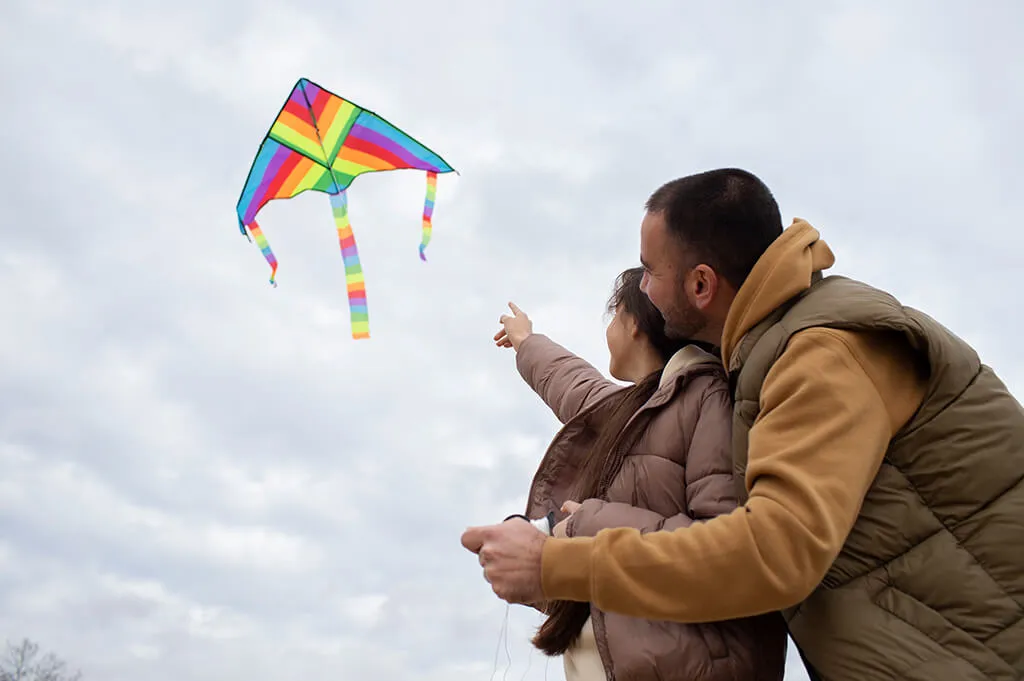 Families gathered in an open field, laughing and flying kites together